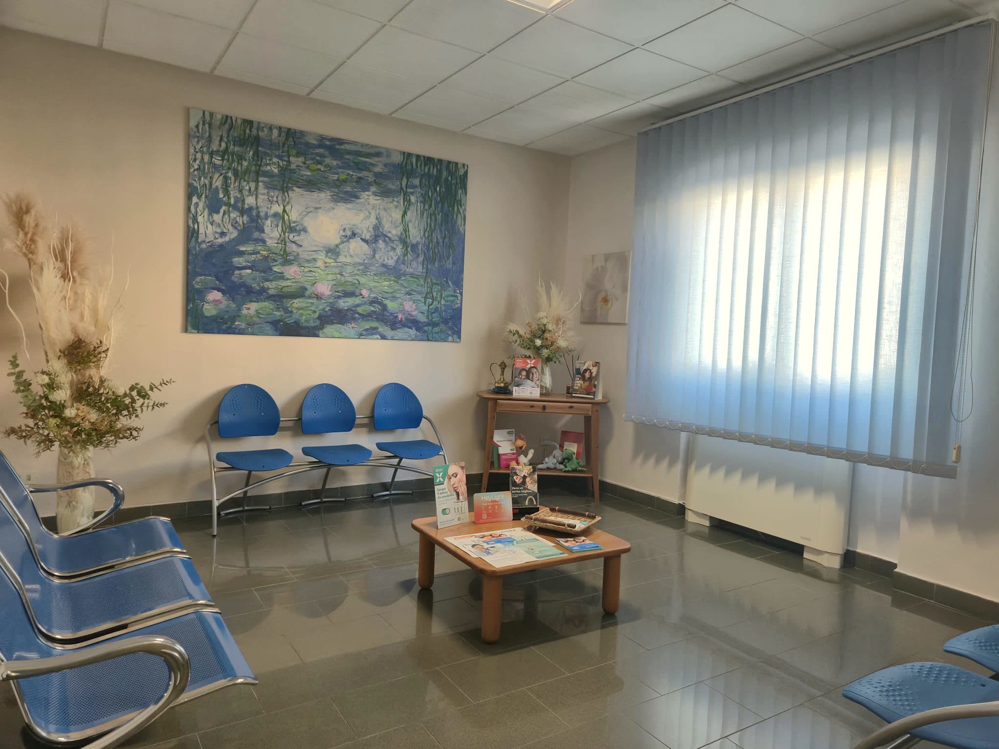 La sala d'attesa dello studio, con le sedute azzurre e il quadro delle ninfee